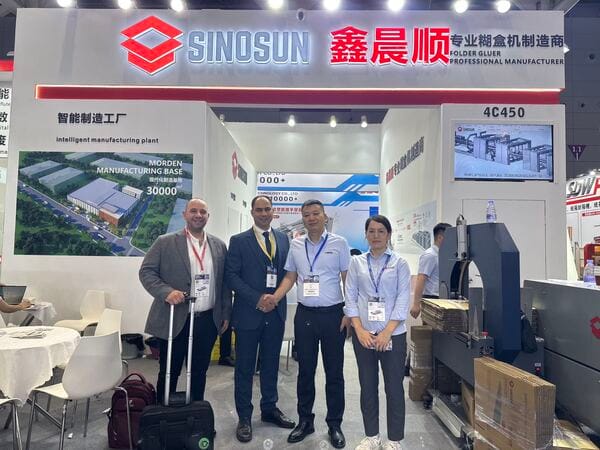 SINOSUN representatives shaking hands with global distributors at a folder gluer exhibition.