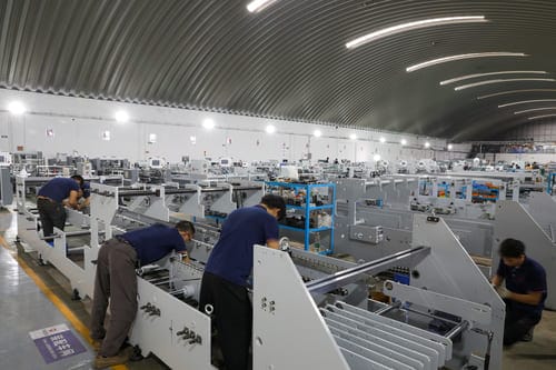 SINOSUN engineer performing precision adjustment on folder gluer machine