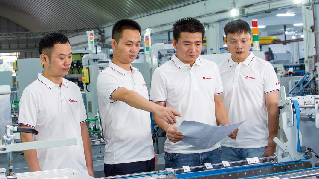 SINOSUN expert engineering team inspecting folder gluer machine blueprints