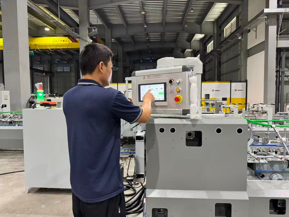Sinosun technical engineer operating the smart touch control panel of an automatic folder gluer machine.